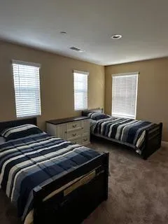 Welcoming resident bedroom with two twin beds and plenty of natural light.